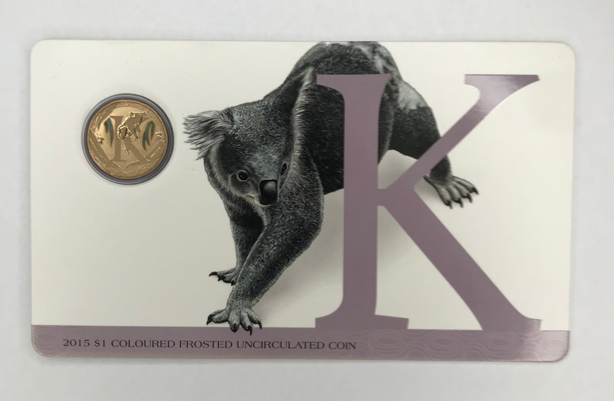 2015 $1 Uncirculated Carded Coin. ‘K’ is for Kindly. Keen For a Smile.
