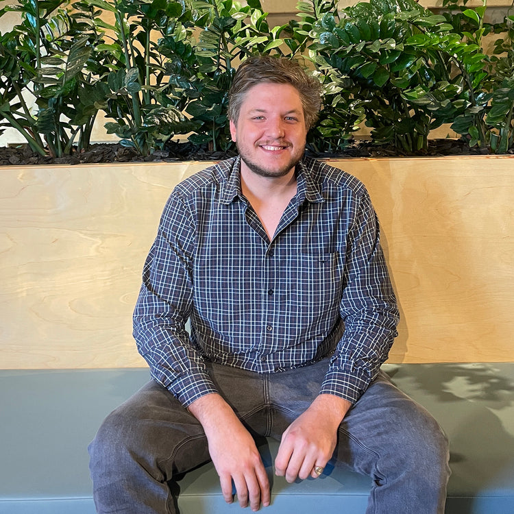 Robbie Colborne, Managing Director of Ensleigh Coins, seated in front of indoor plants