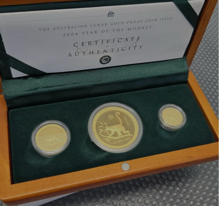 Three encapsulated gold proof coins in their presentation box with a 2004 Year of the Monkey certificate